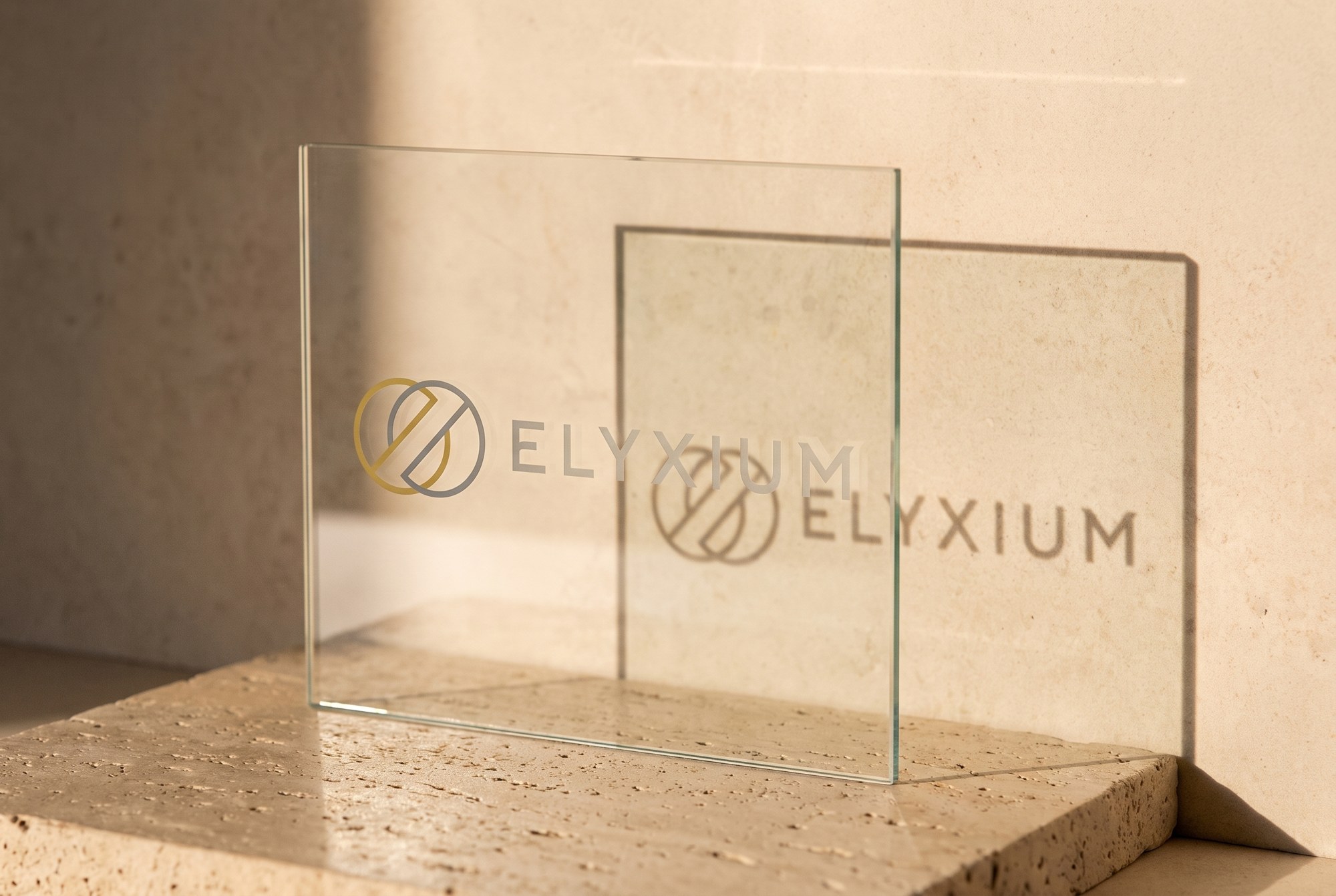 Elyxium mark and wordmark etched into transparent glass