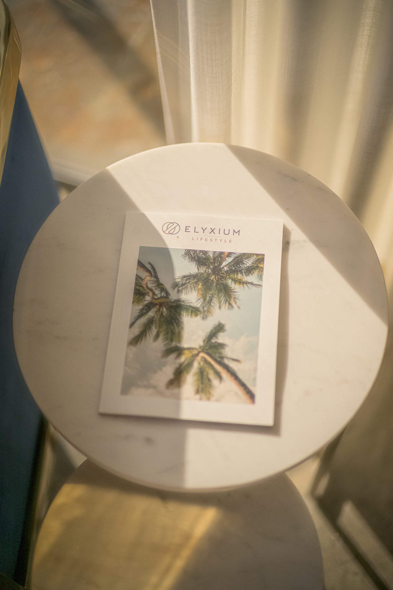 Elyxium Lifestyle booklet on a circular table in afternoon light