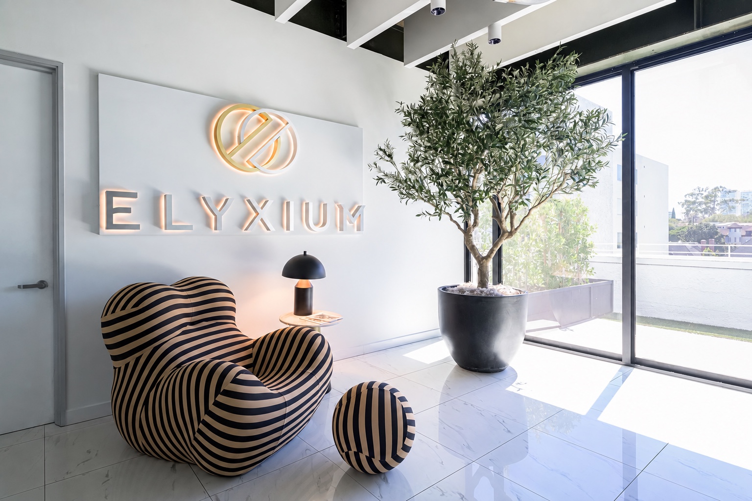 Elyxium’s branded reception, with the gold mark and wordmark on the wall